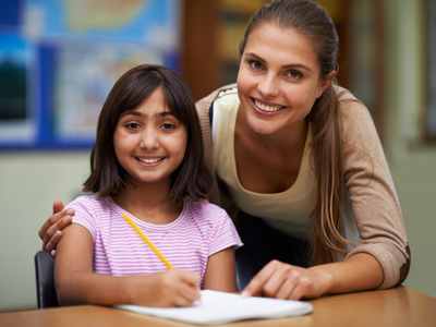 Teacher and girl writing at a desk