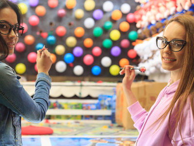 Two girls throwing darts in an amusement park