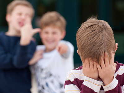 Two young boys bullying a smaller child