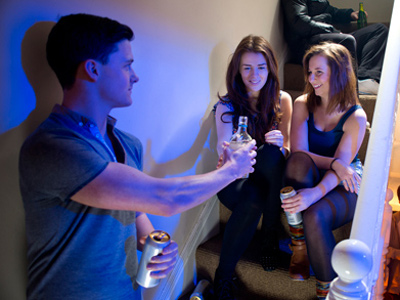 Teenage boy offering alcohol to girls at a party