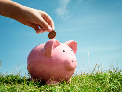 Child's hand putting money into a piggybank