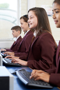 Secondary school class in uniforms studying on computers