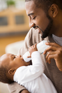 Smiling father feeding his baby